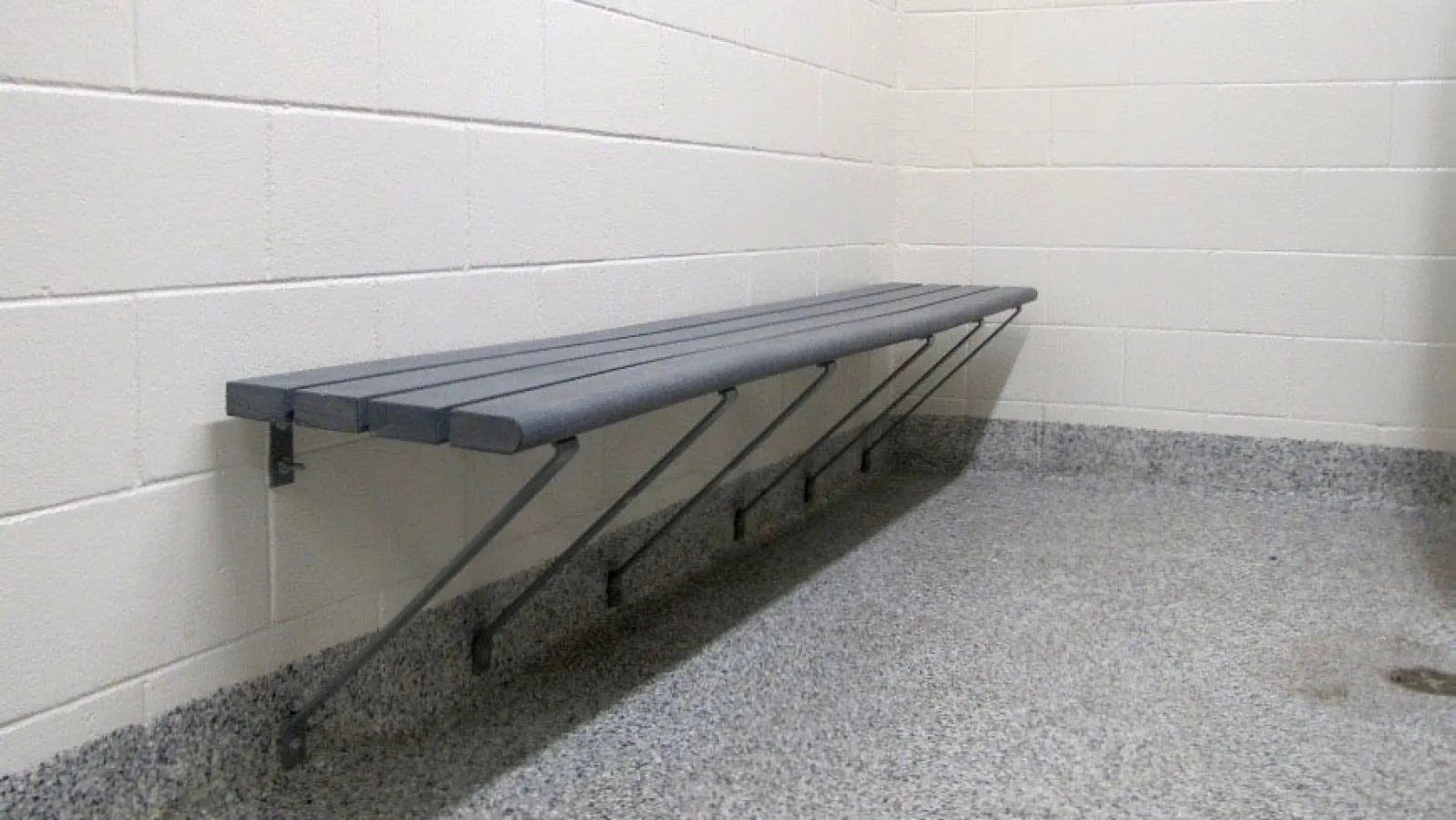 Wall-mounted bench seating provides a space to rest in a change room or similar indoor environment. The bench features recycled plastic lumber slats and a metal frame.