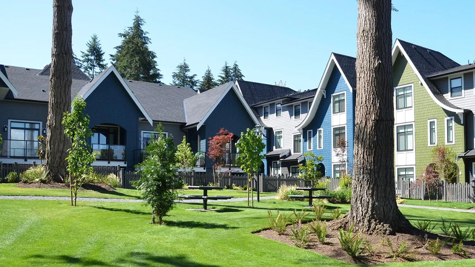 These single pedestal picnic tables provide a place to relax in a grassy common area. The tables are perfect for enjoying a meal or conversation in this residential community.