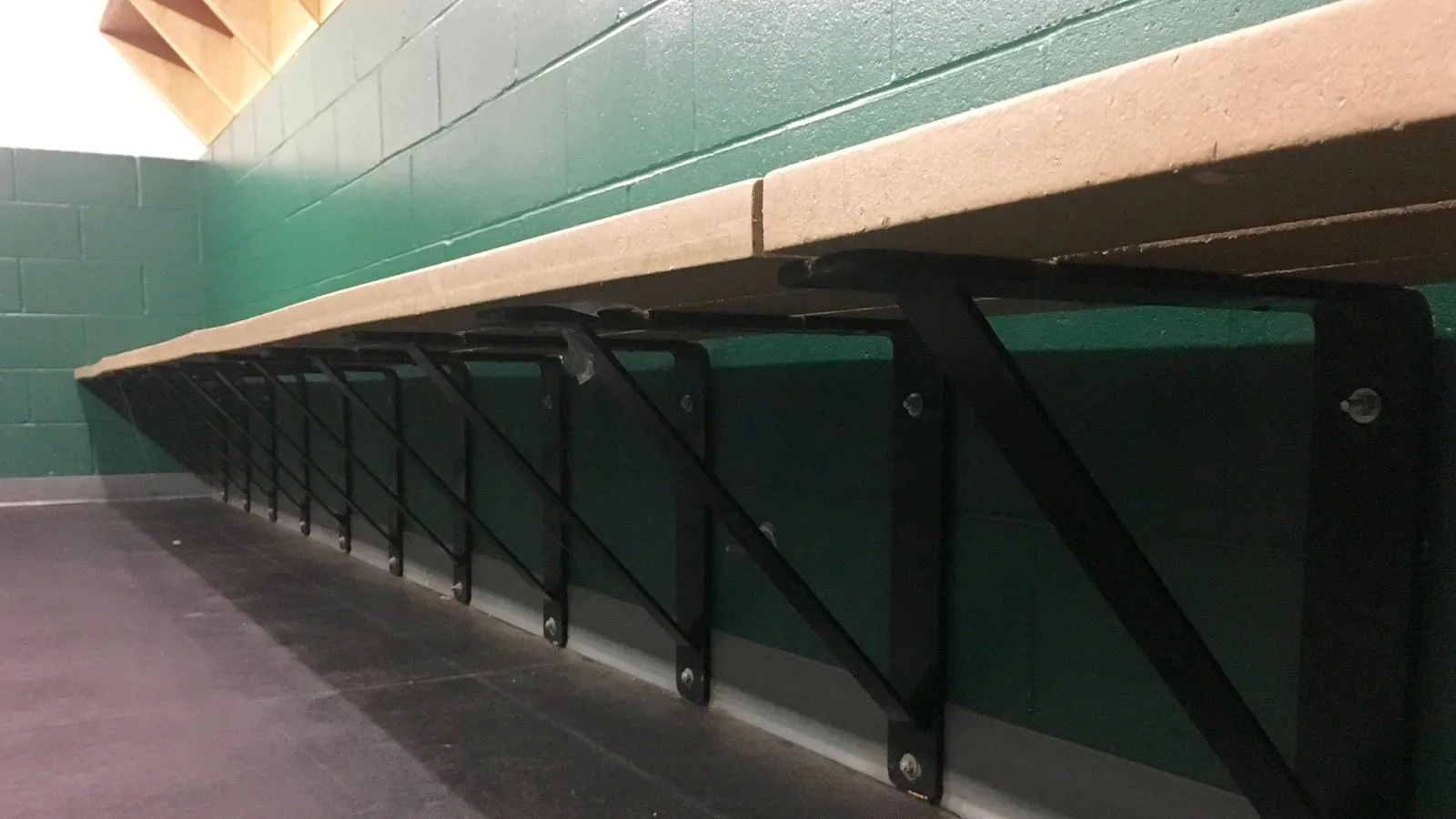 Wall-mounted bench seating with recycled plastic lumber and black powder-coated metal supports. This bench is suitable for indoor use in changing rooms or hallways.
