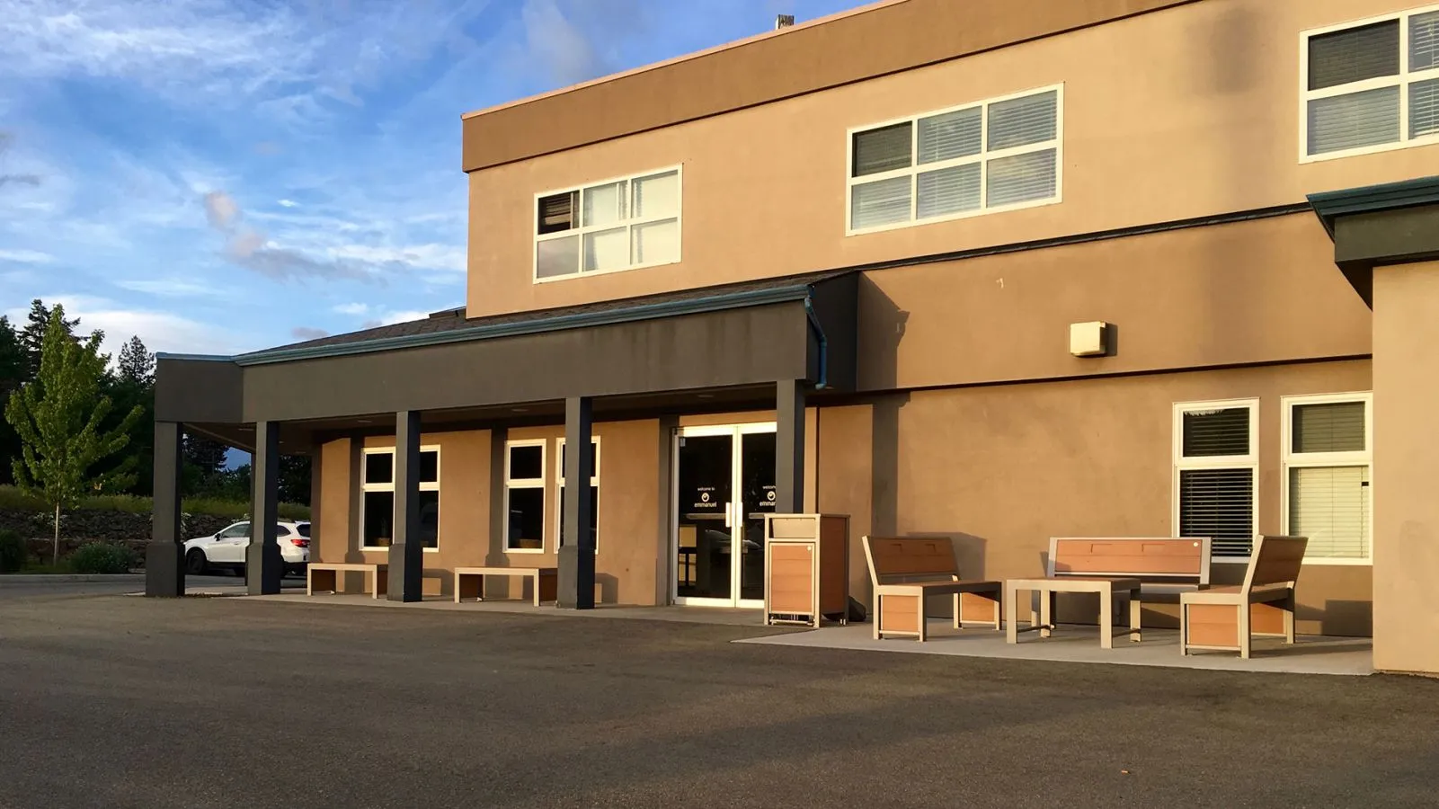 Outdoor seating area with Urban Form benches and a waste receptacle outside Emmanuel Church. The furniture provides a comfortable and functional space for visitors.