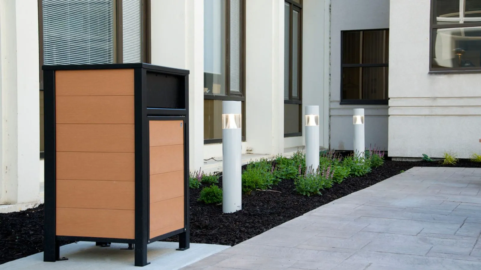 Urban Form waste receptacle featuring recycled plastic lumber and a black powder-coated frame. This durable and stylish litter bin is perfect for high-traffic outdoor areas.