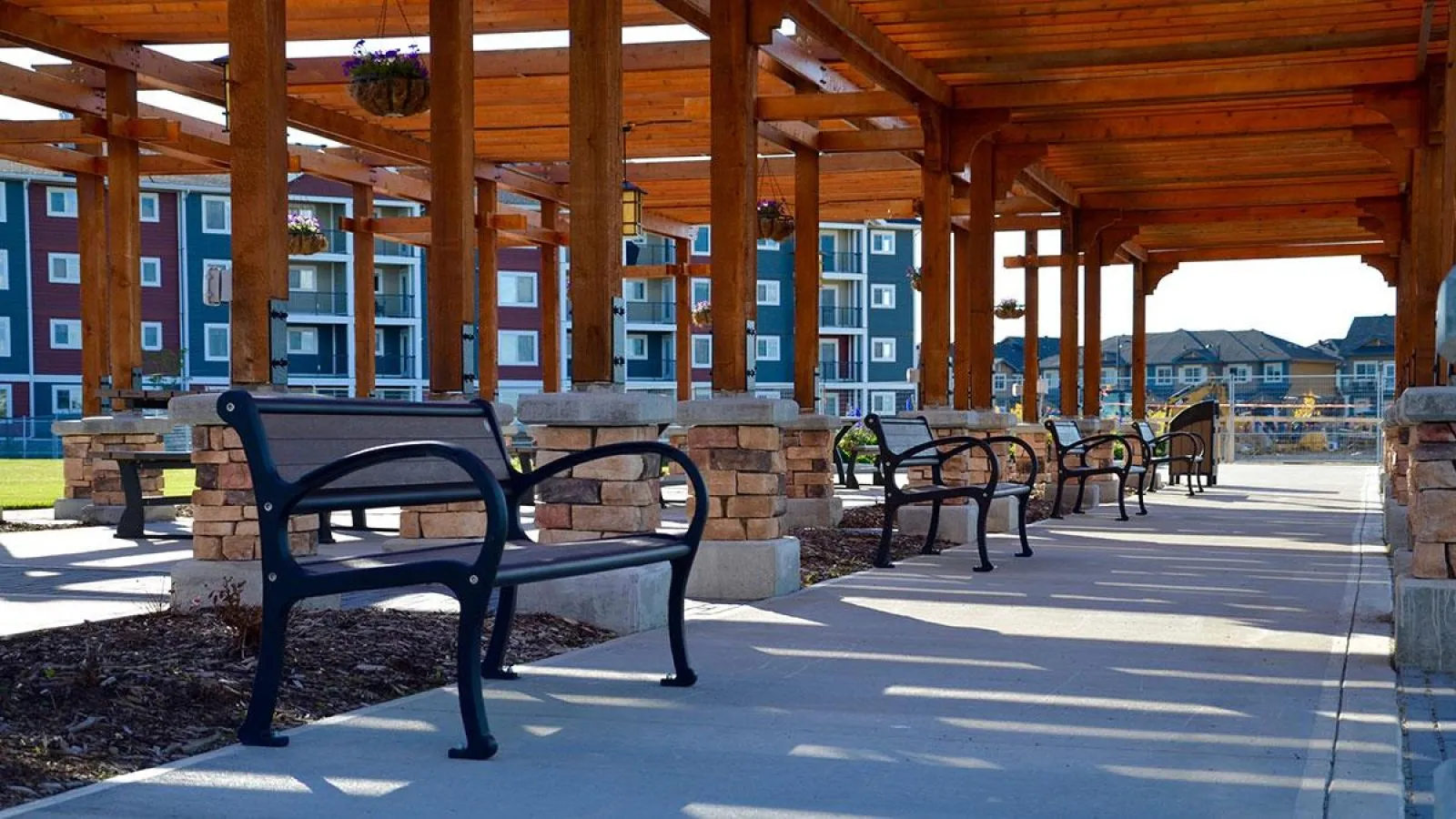 Mountain Classic benches line a covered walkway in Chappelle Gardens, Edmonton. These durable benches offer comfortable seating in a community space.