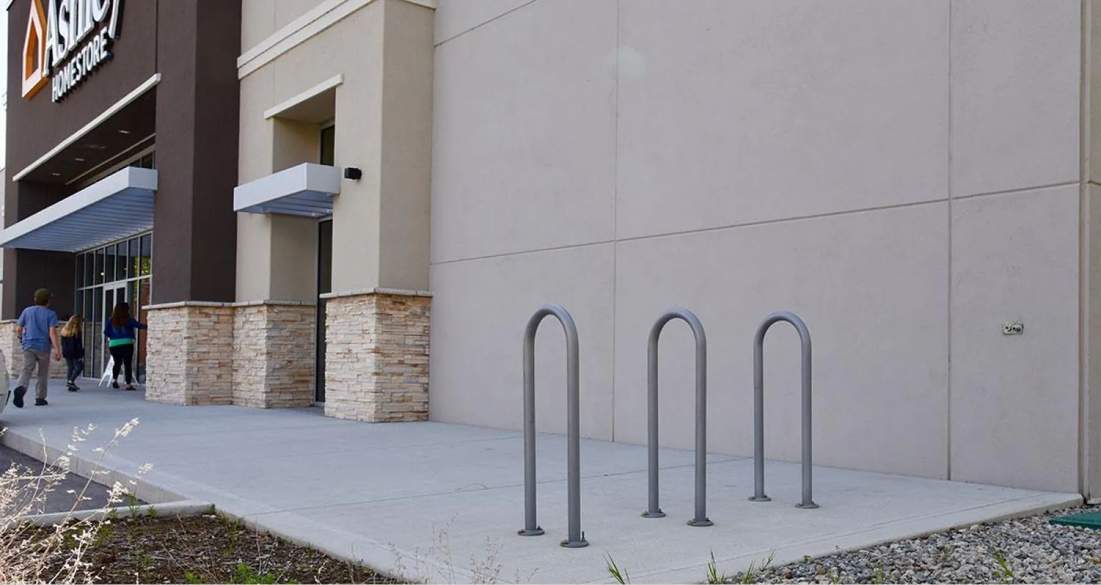 Three surf bike racks provide convenient parking outside a commercial building. The racks are finished in a neutral gray powder coat.