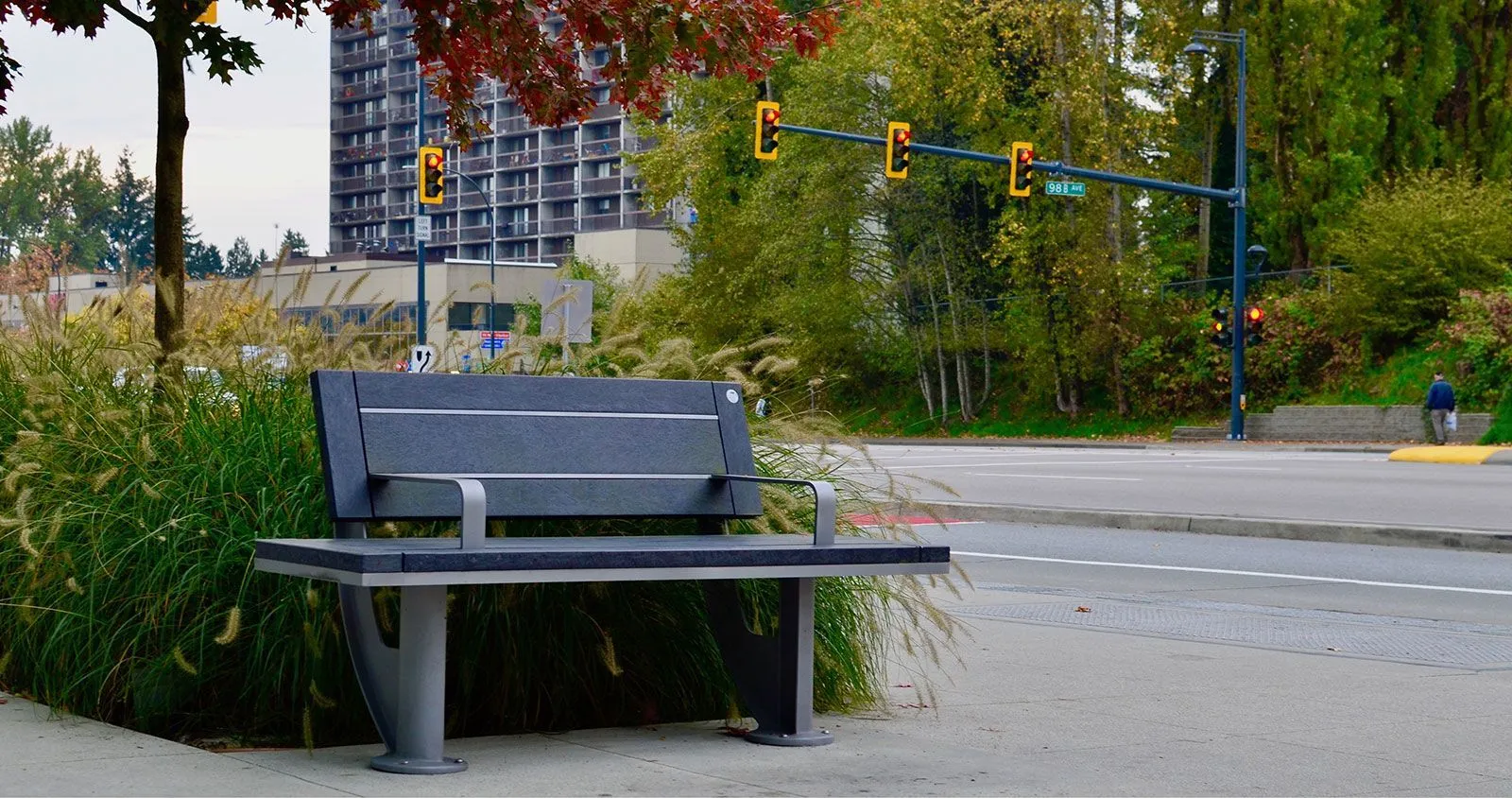 A SurRe bench provides seating along a sidewalk in Surrey, British Columbia. The bench features recycled plastic lumber and a powder-coated metal frame.