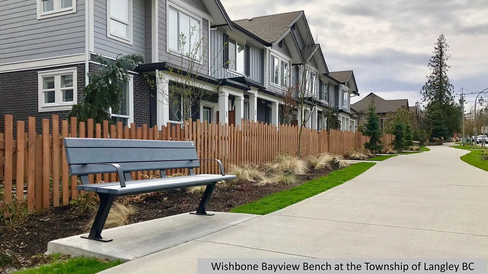 Bayview bench provides comfortable seating along a pathway in a residential area. The bench features recycled plastic lumber and a powder-coated metal frame.
