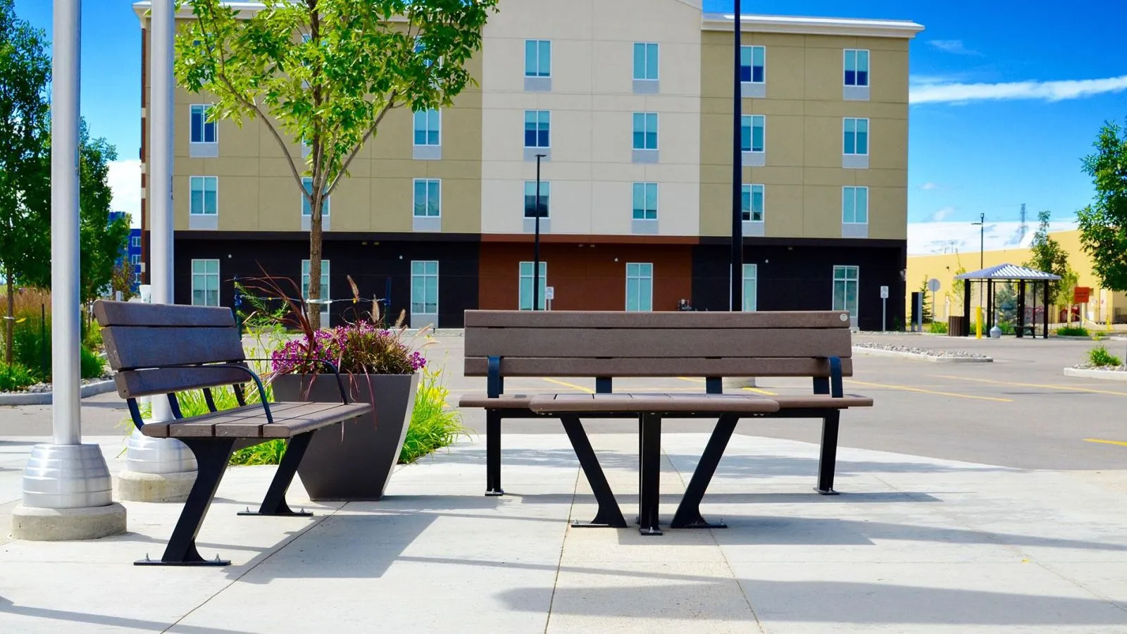 Bayview benches and coffee table enhance an outdoor space. The benches feature recycled plastic lumber and powder-coated metal frames, providing durable and stylish seating.