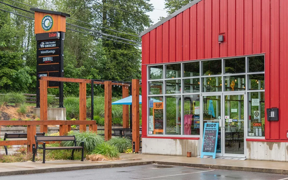 A Beselt bench sits outside a red building in Chemainus Village Square. The bench features black recycled plastic lumber.