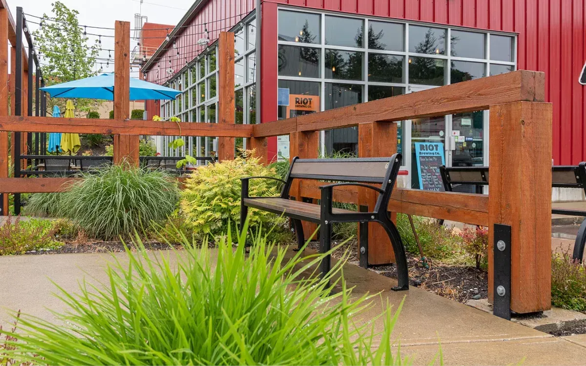 A Beselt bench provides seating outside Riot Brewing Co. in Chemainus, British Columbia. The bench features recycled plastic lumber and a black powder-coated frame.