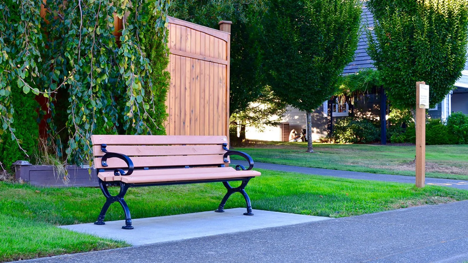 A Classic bench provides seating along a pathway in the Crown Isle Subdivision in Courtenay, British Columbia. The bench features recycled plastic lumber and a powder-coated metal frame.