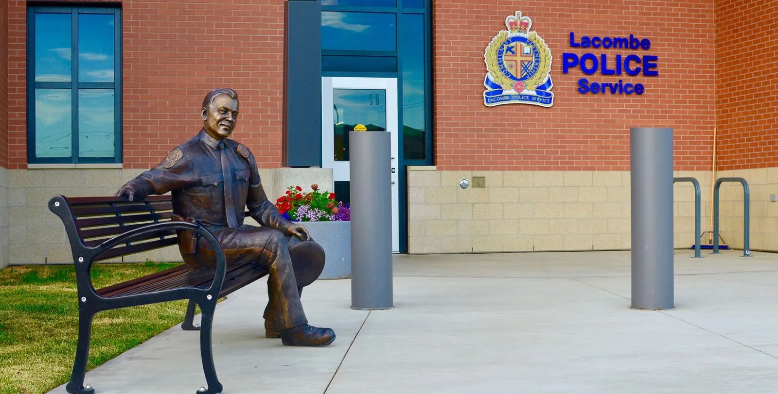 A classic bench provides seating outside the Lacombe Police Service in Alberta. The bench features recycled plastic lumber slats and a powder-coated metal frame.