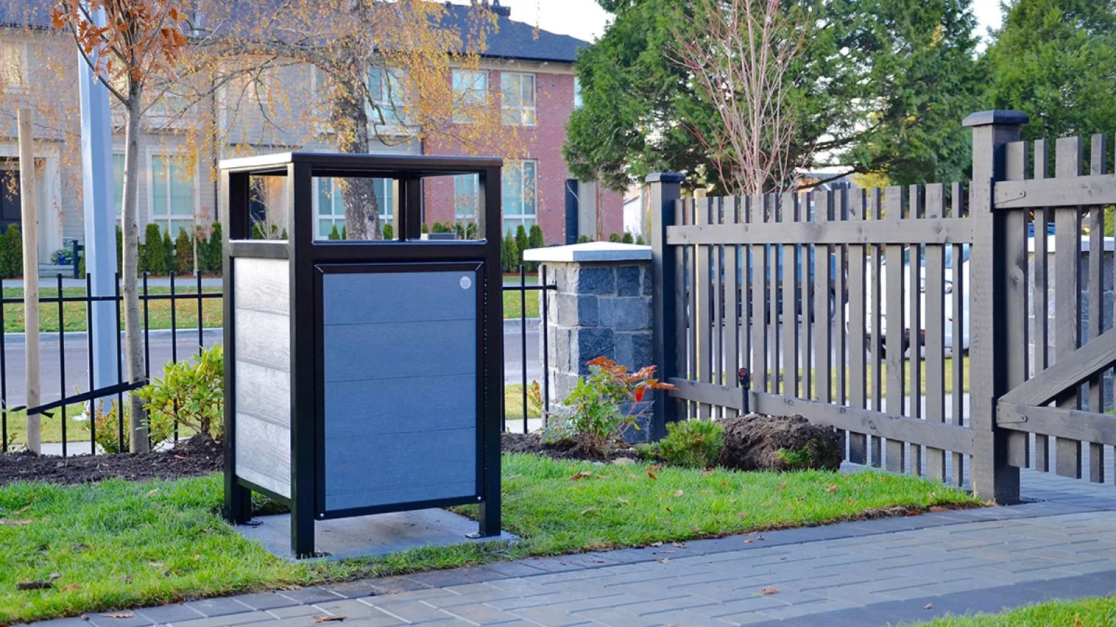 Easy Access Urban Form Waste Receptacle provides convenient disposal in a residential setting. The receptacle features recycled plastic lumber panels and a durable powder-coated frame.
