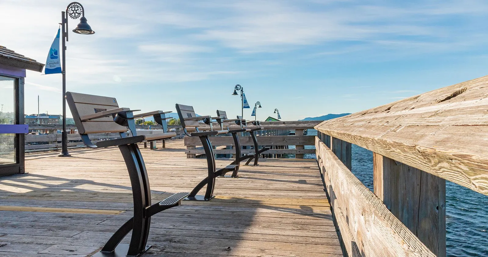Row of fisherman's chairs line a wooden pier overlooking the water. These chairs provide comfortable seating with a footrest and armrests, perfect for enjoying the waterfront view.