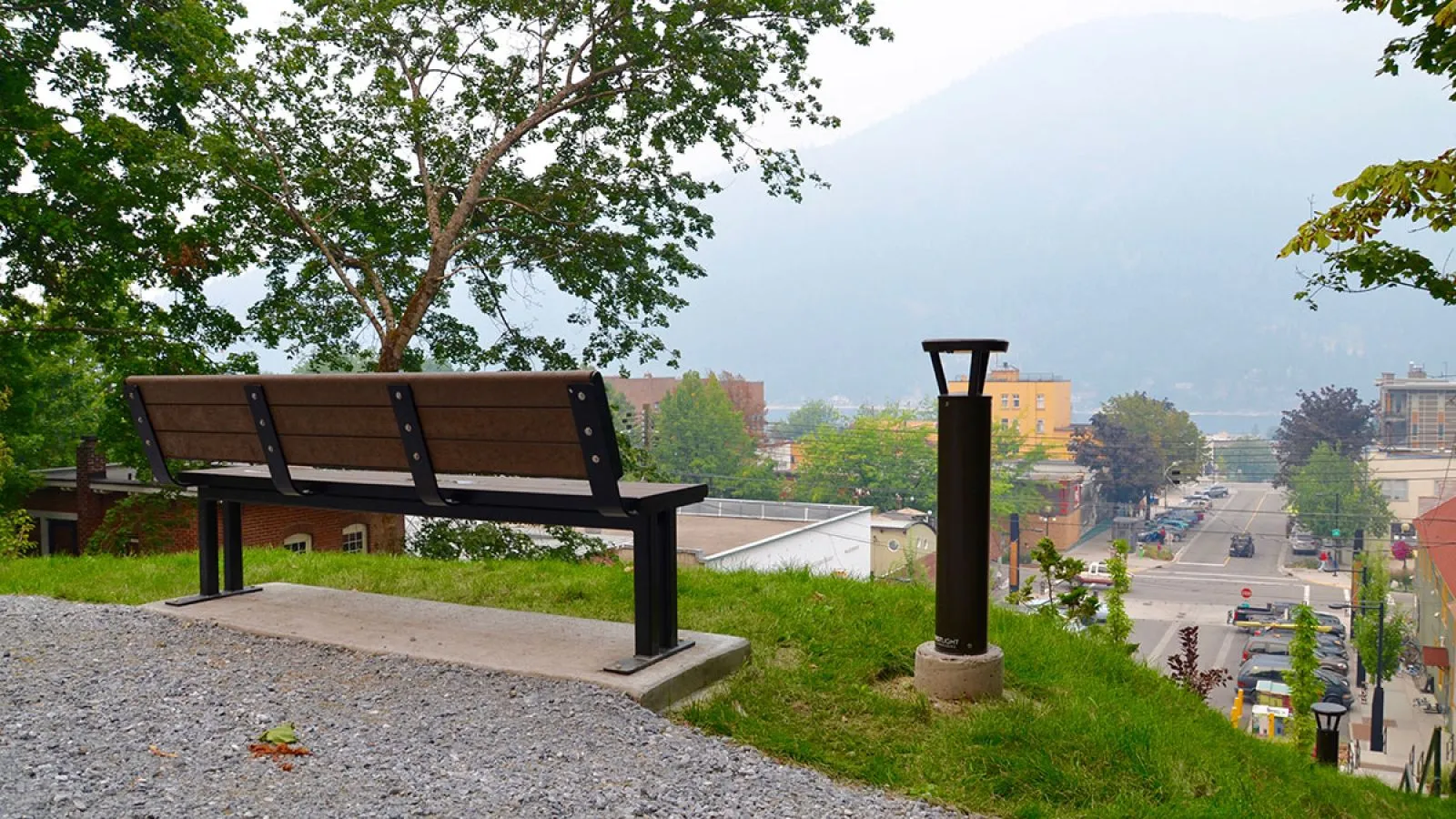 A Larson bench offers a scenic view of Nelson, BC. The bench features recycled plastic lumber and a powder-coated metal frame.