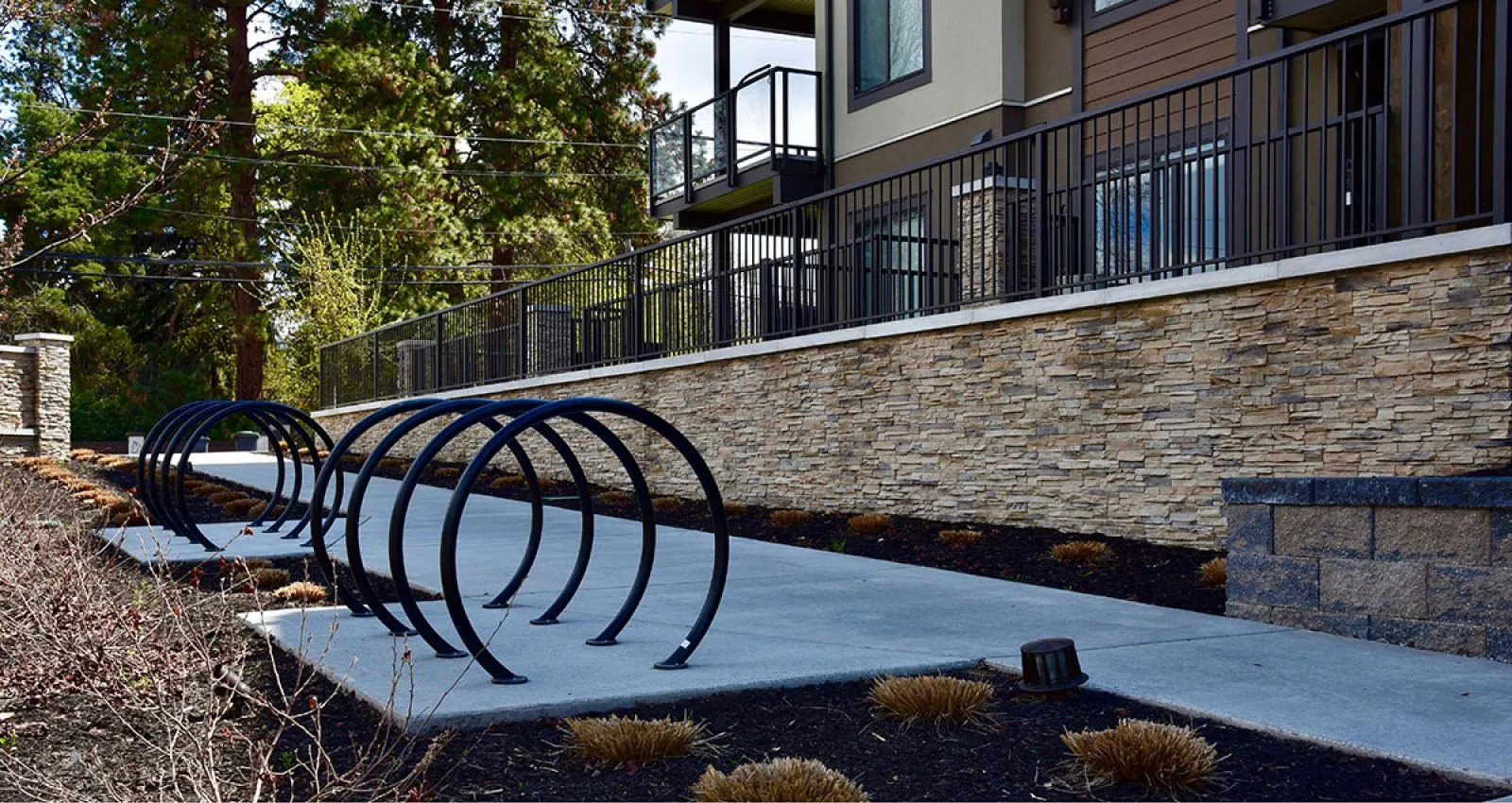 LOOP bike racks provide convenient and secure bicycle parking along a walkway. The black powder-coated racks complement the surrounding landscape and architecture.