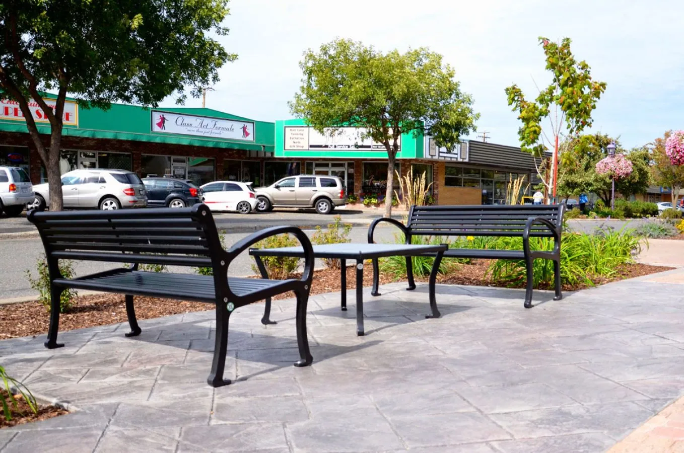 Mountain Classic benches and coffee table create a welcoming outdoor seating area in a commercial setting. The black powder-coated metal frames and recycled plastic lumber offer durability and style.