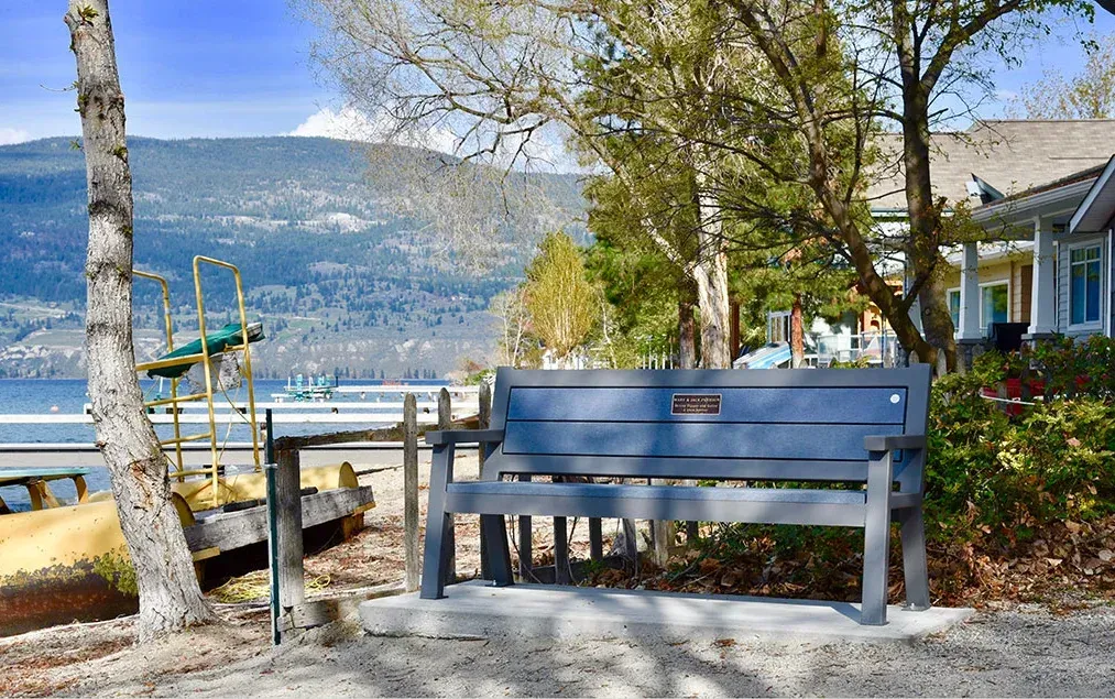 A Rutherford bench provides seating along the waterfront. The bench features recycled plastic lumber and a powder-coated metal frame.