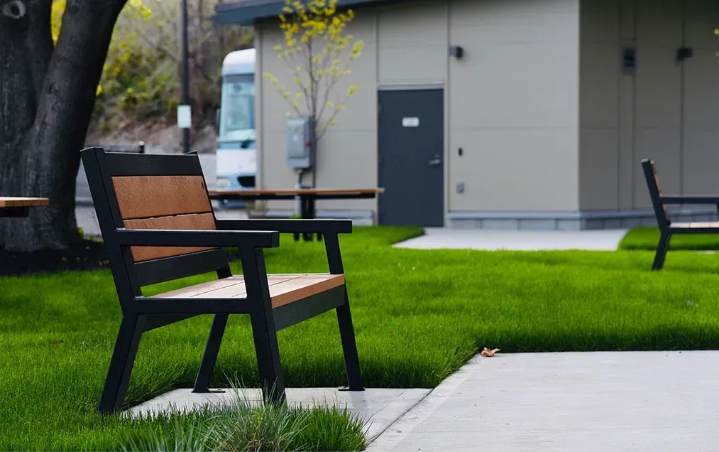 Rutherford Wide Body Bench provides comfortable seating in an outdoor setting. The bench features recycled plastic lumber and a powder-coated metal frame.