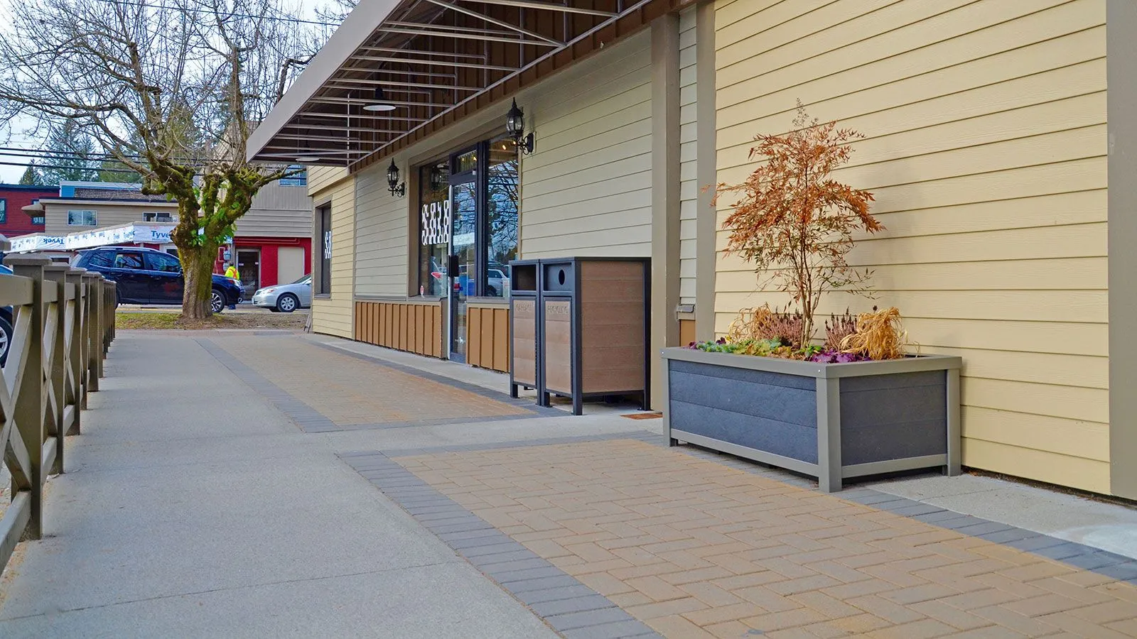 Urban Form rectangular self-watering planter box enhances a commercial space. The planter features recycled plastic lumber and a powder-coated metal frame.