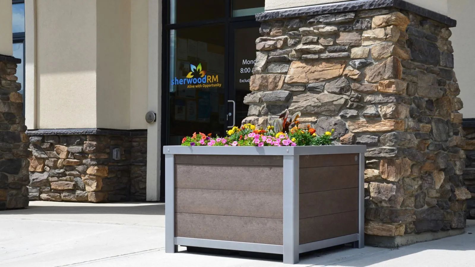 Urban Form square planter box with flowers outside Sherwood Regional Municipality. The planter features recycled plastic lumber and a powder-coated metal frame.