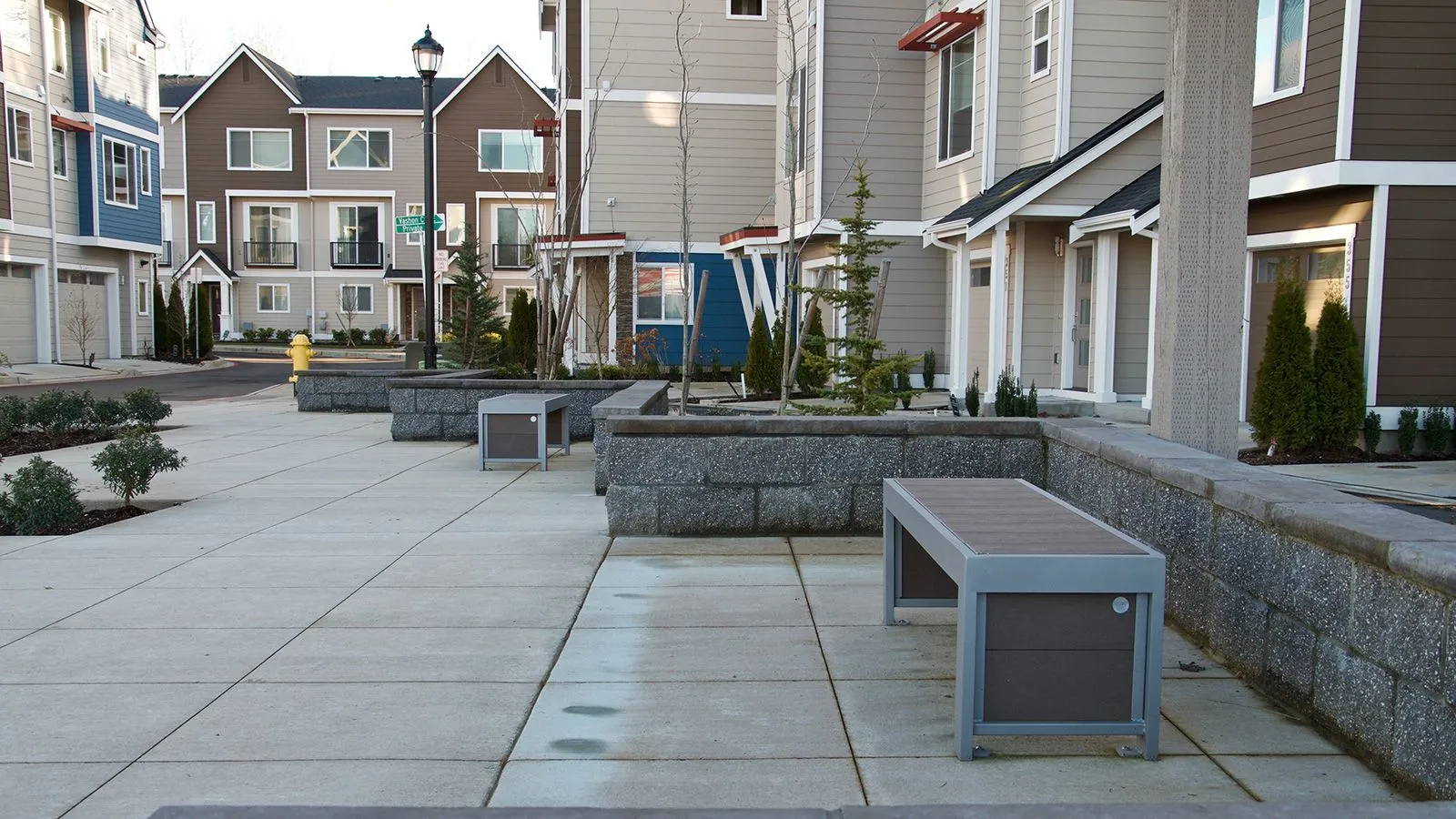Urban Form benches provide seating in a residential area. These straight benches feature recycled plastic lumber and powder-coated metal frames.