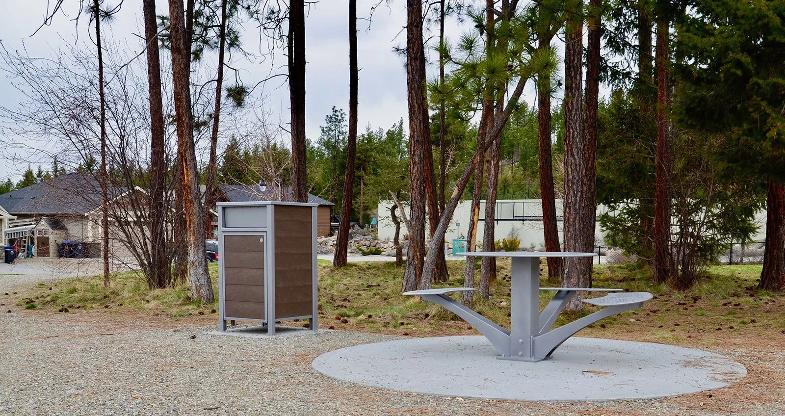 Wheelchair-accessible picnic table and waste receptacle create an inviting outdoor space. The table features a circular concrete pad and the bin has recycled plastic lumber panels.