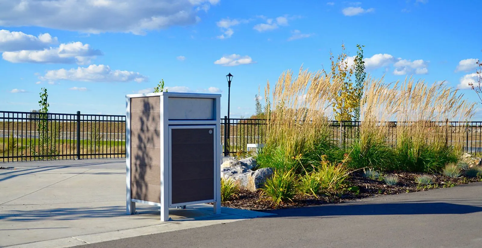 Urban Form waste receptacle in a park setting. The bin features recycled plastic lumber and a powder-coated metal frame.