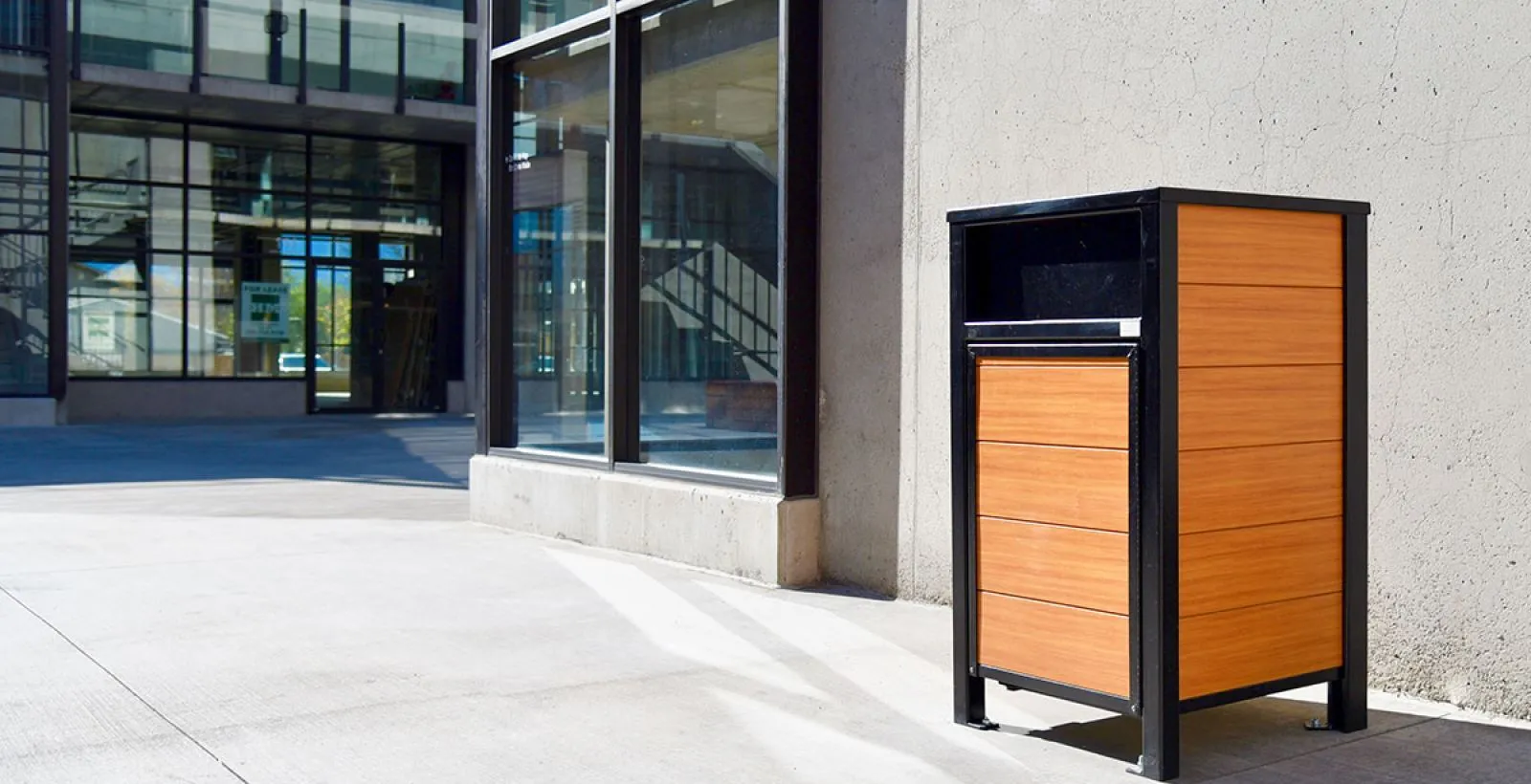 Urban Form waste receptacle featuring recycled plastic lumber and a powder-coated metal frame. This litter bin is suitable for commercial or public spaces.