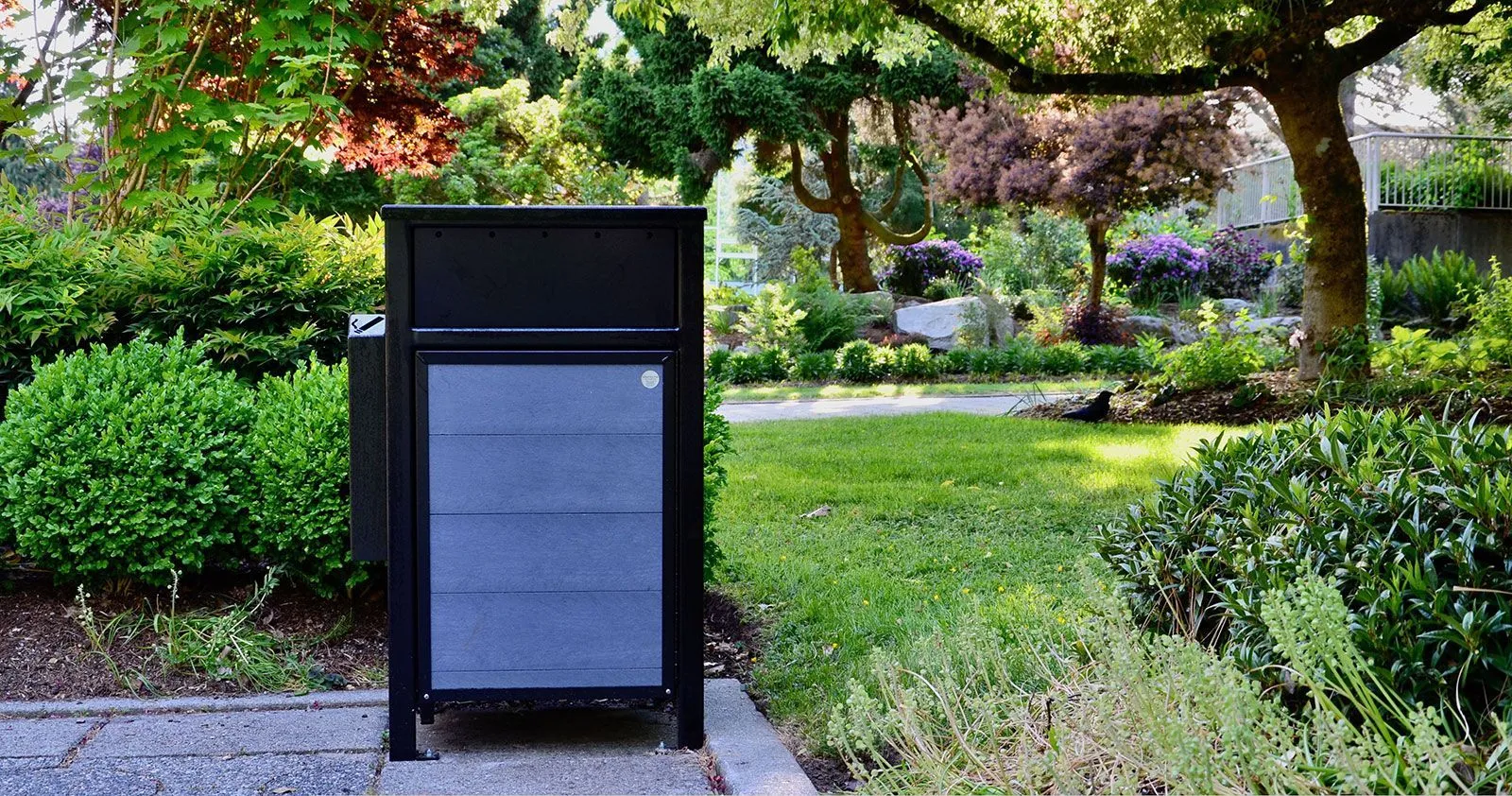 Urban Form waste receptacle with an ashtray, featuring recycled plastic lumber and a powder-coated metal frame. This durable litter bin is suitable for parks, streetscapes, and other outdoor settings.