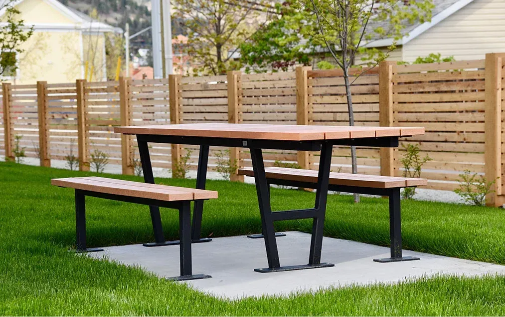 Wheelchair accessible picnic table with recycled plastic lumber top and black powder-coated frame. This outdoor table provides an inclusive space for dining and gathering in a park or recreational area.
