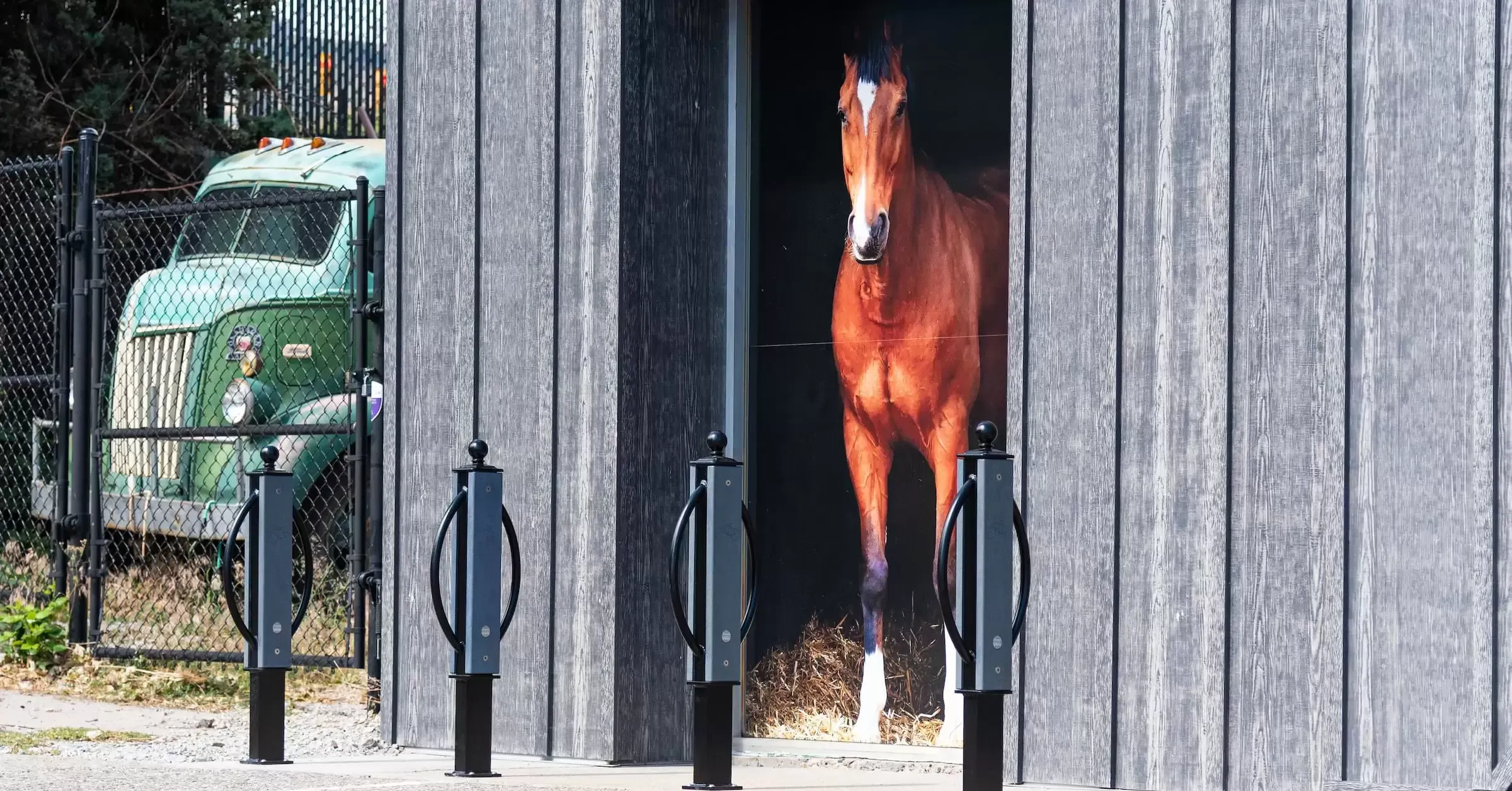 Three bike racks stand in front of a building with a horse mural. These racks provide secure parking for bicycles.