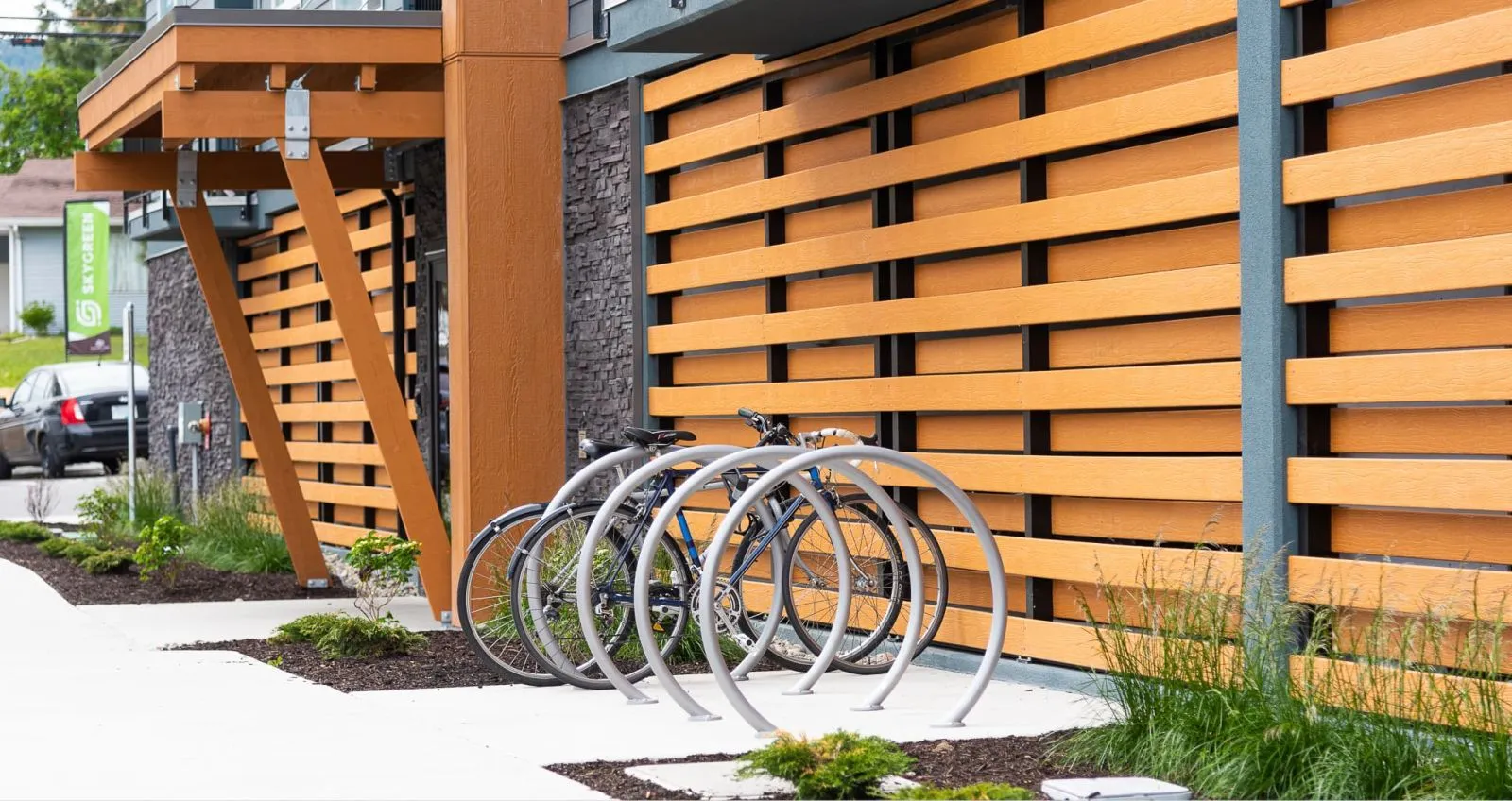Bike racks provide secure parking outside the Skygreen Apartments in West Kelowna, British Columbia. The racks complement the building's modern design and landscaping.