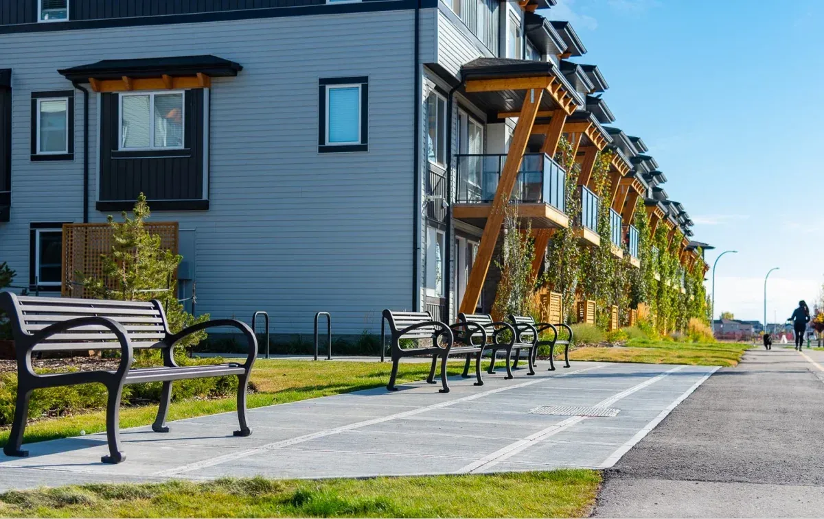 Mountain Classic benches line a walkway in a residential area. The benches feature a black powder coat finish.