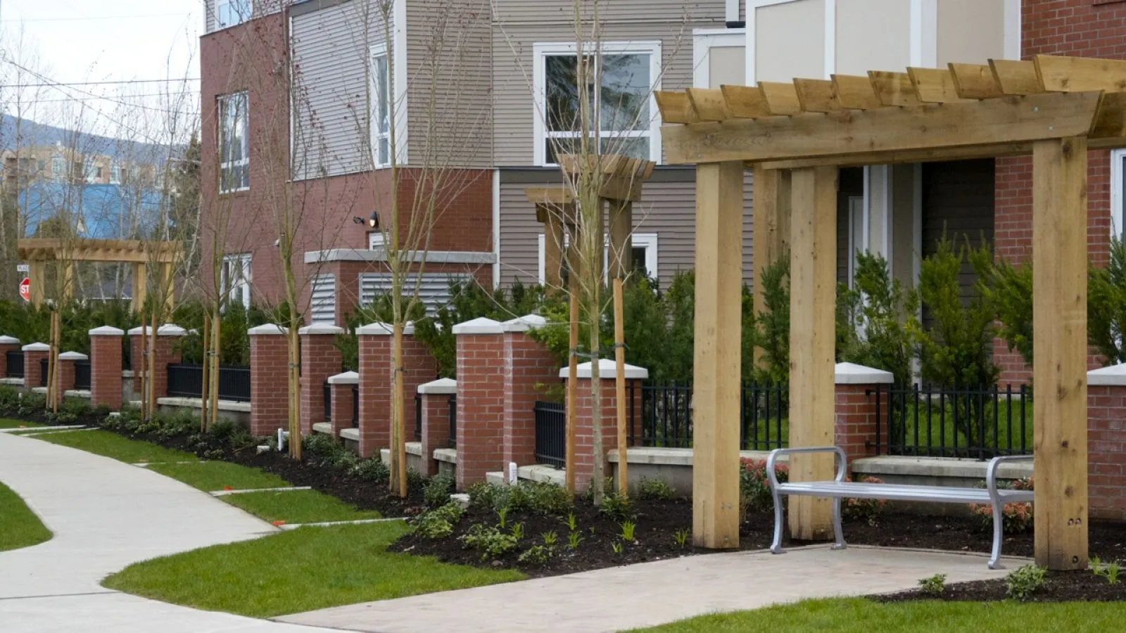 A Mountain Classic Straight Bench provides seating along a walkway in Maple Ridge, British Columbia. The bench features a metal frame and recycled plastic lumber.