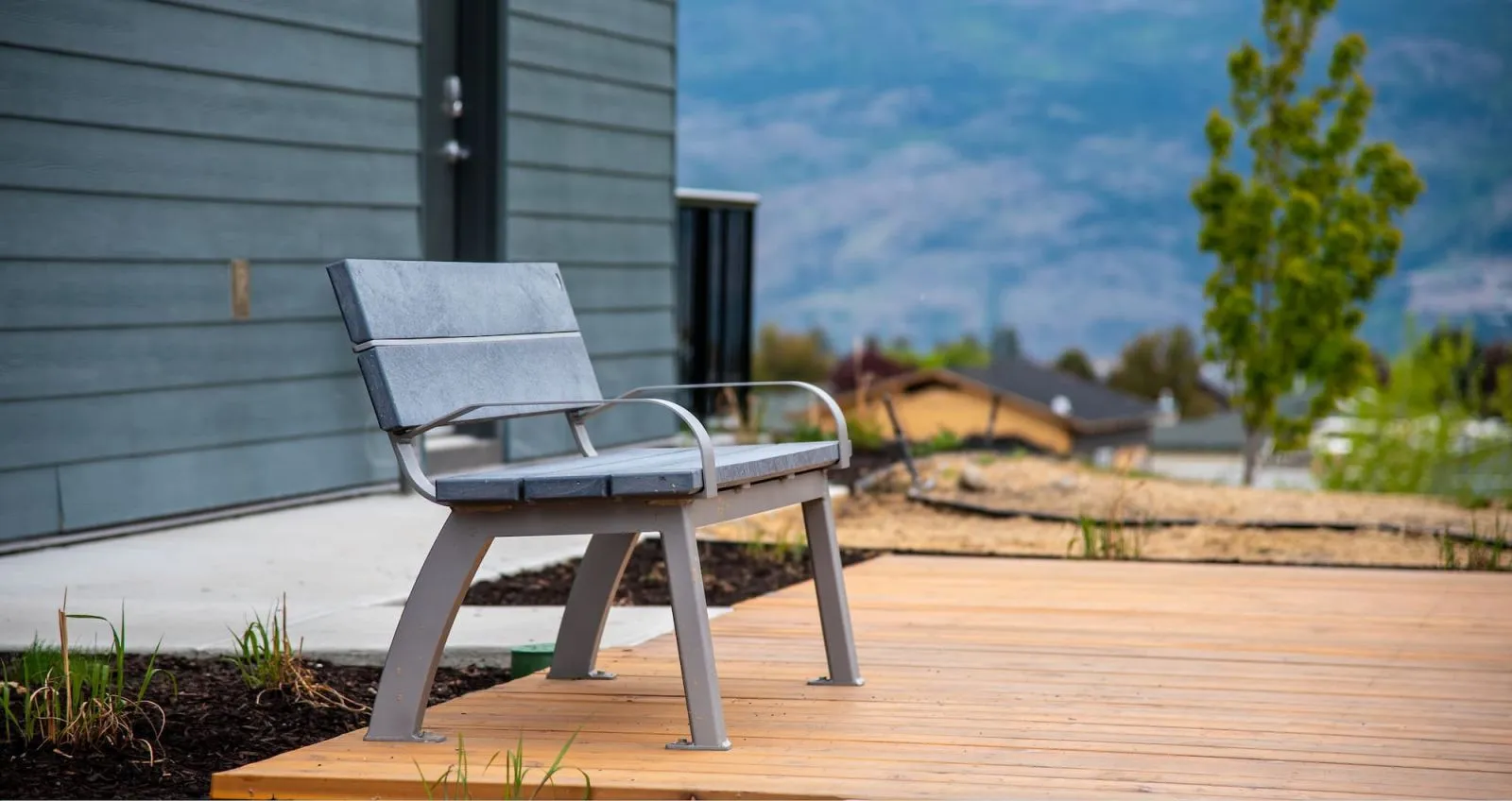 Aylesbury bench with a metal frame and recycled plastic lumber seating, situated on a wooden deck. The bench offers a place to relax and enjoy the surrounding view.