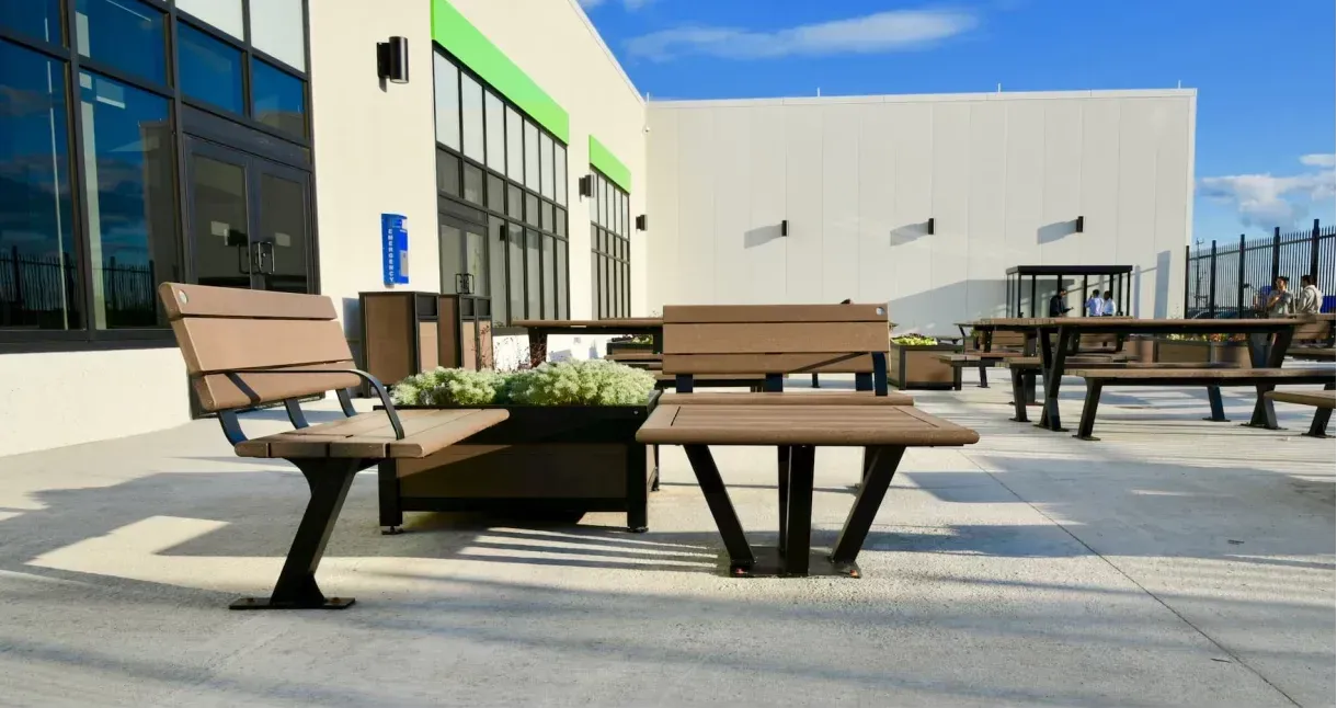 Bayview bench and planter combo with a square coffee table create a welcoming outdoor seating area. The recycled plastic lumber in a wood-tone finish complements the black powder-coated metal frames.