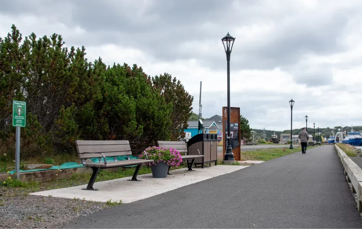 Bayview benches provide seating along a waterfront walkway. A Modena 2 Stream Recycling Station is also visible.