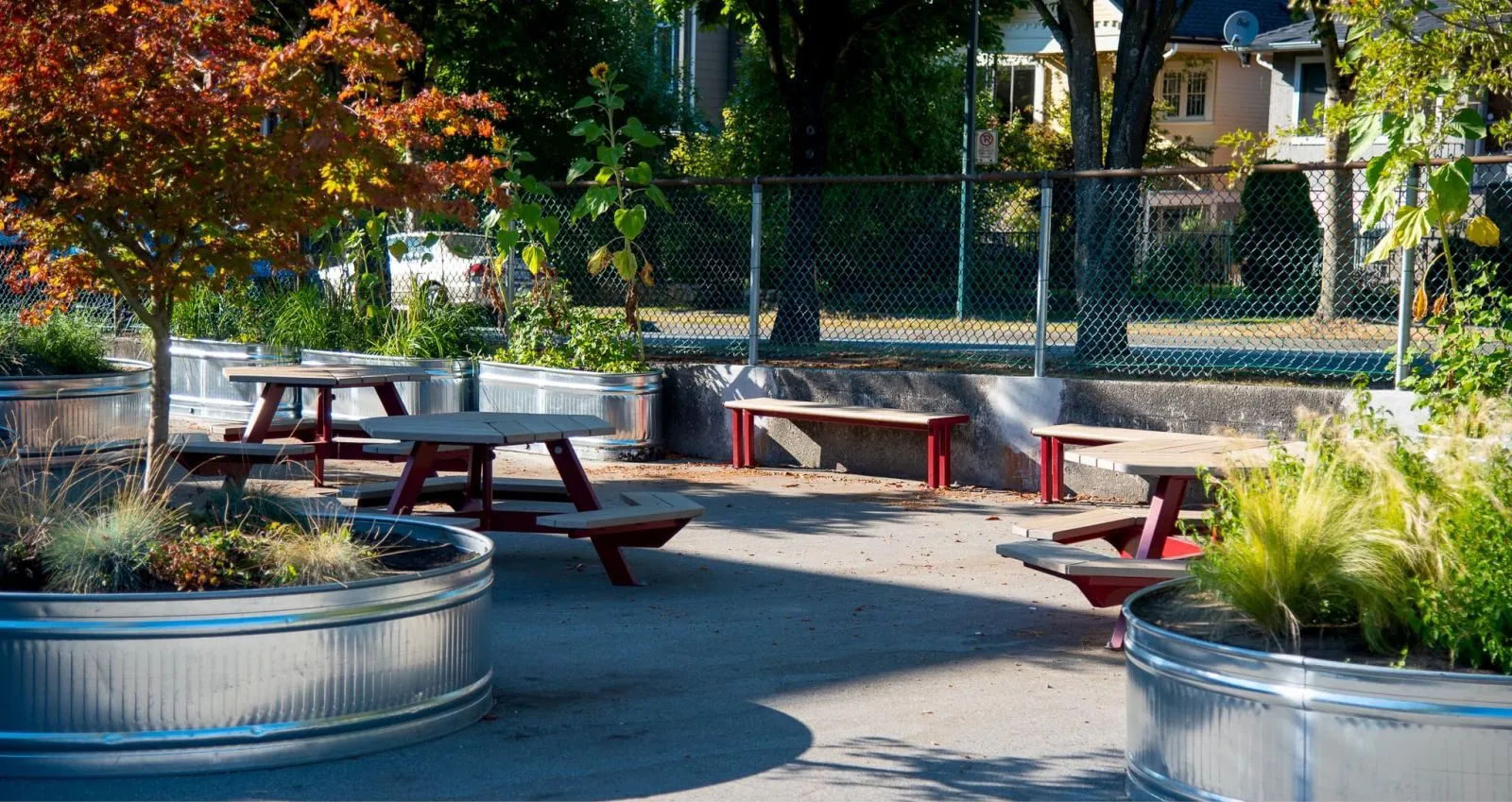 Galvanized steel planters and picnic tables create an inviting outdoor space at Hastings Elementary School. The tables feature recycled plastic lumber tops and red powder-coated frames.