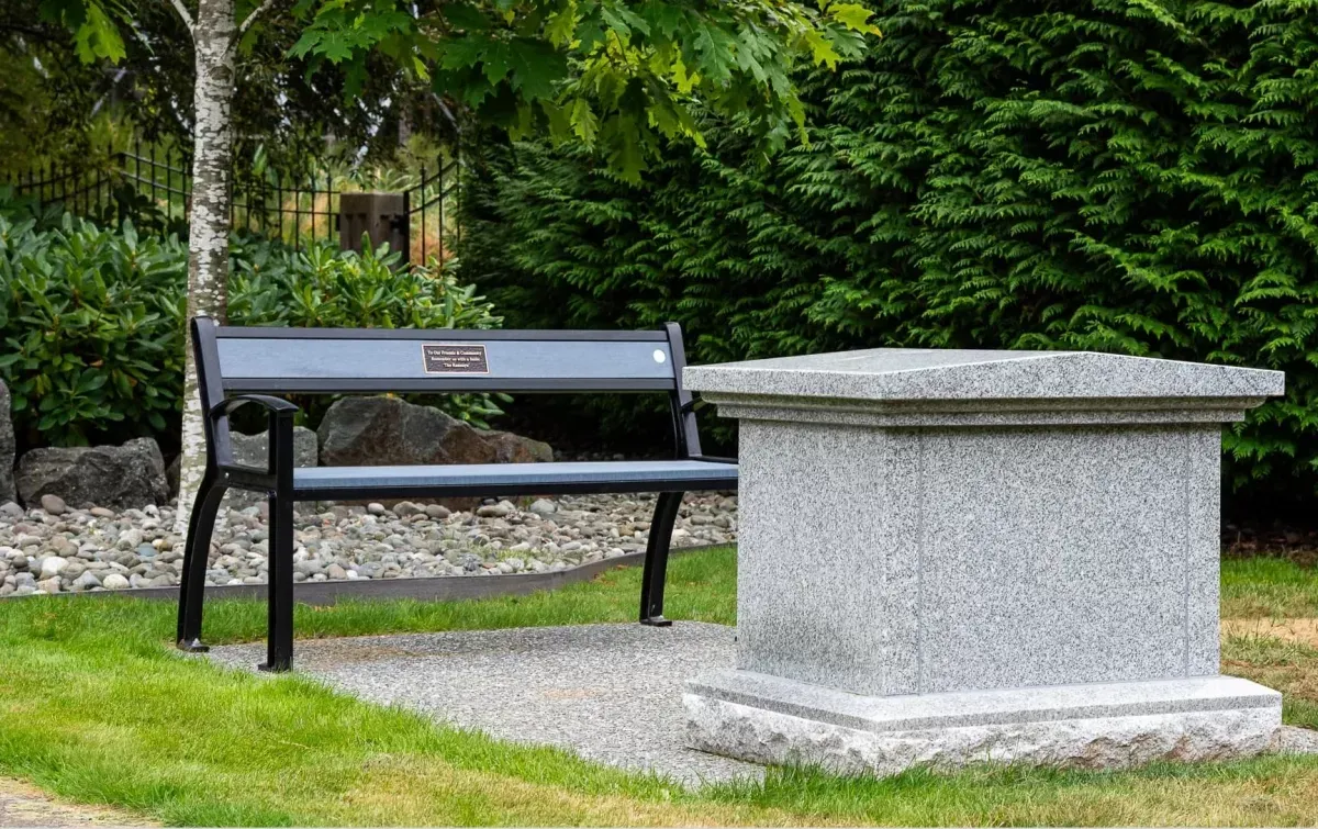 A Beselt bench provides seating in a memorial garden setting. The bench features recycled plastic lumber and a powder-coated metal frame.