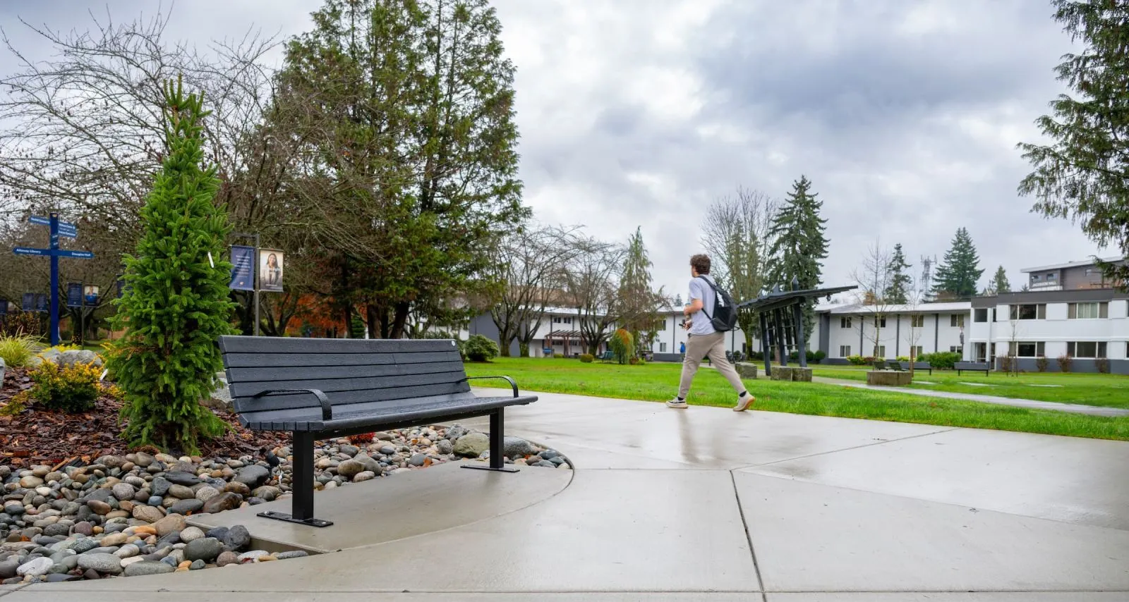 A Chat Bench provides seating along a walkway on the campus of Trinity Western University in Langley, British Columbia. The bench features recycled plastic lumber and a powder-coated metal frame.