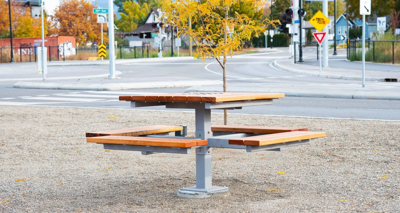 A single pedestal picnic table offers a unique seating arrangement in an outdoor setting. The table features a wooden top and seats with a gray metal pedestal base.