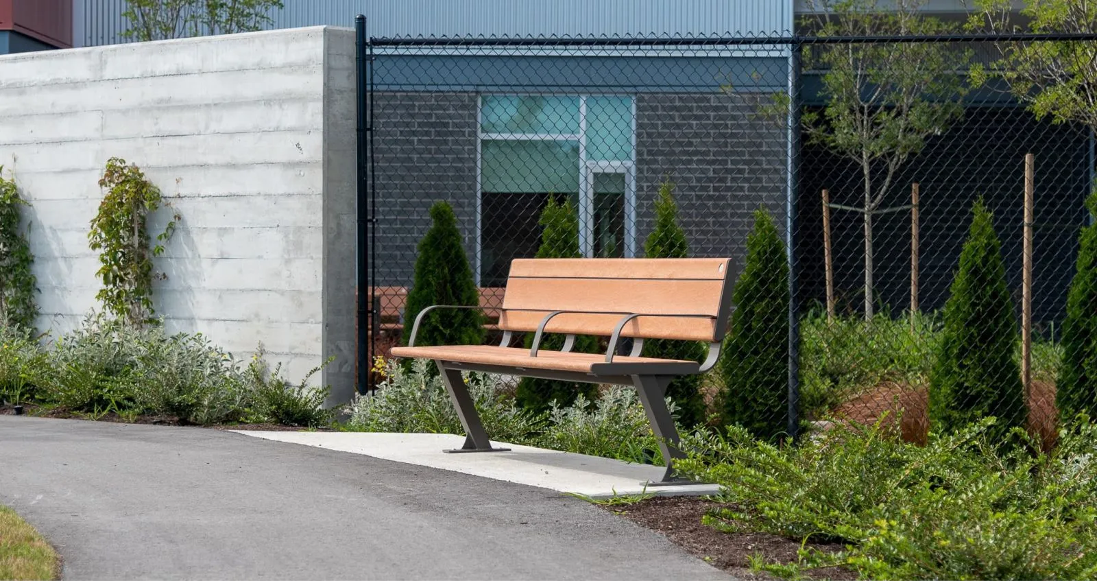 Bayview Plus bench provides comfortable seating in a landscaped area. The bench features recycled plastic lumber and a powder-coated metal frame.
