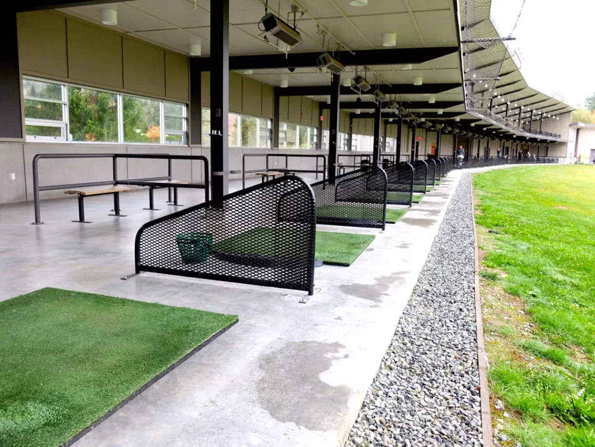 Custom straight benches line the covered driving range at Riverway Golf Course in Burnaby, British Columbia. The benches provide seating for golfers between practice sessions.