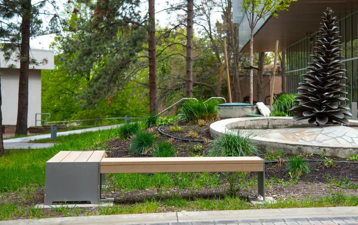 A Hutch Backless Bench with a side table is installed at Thompson Rivers University in Kamloops, British Columbia. The bench features recycled plastic lumber and a powder-coated metal frame.