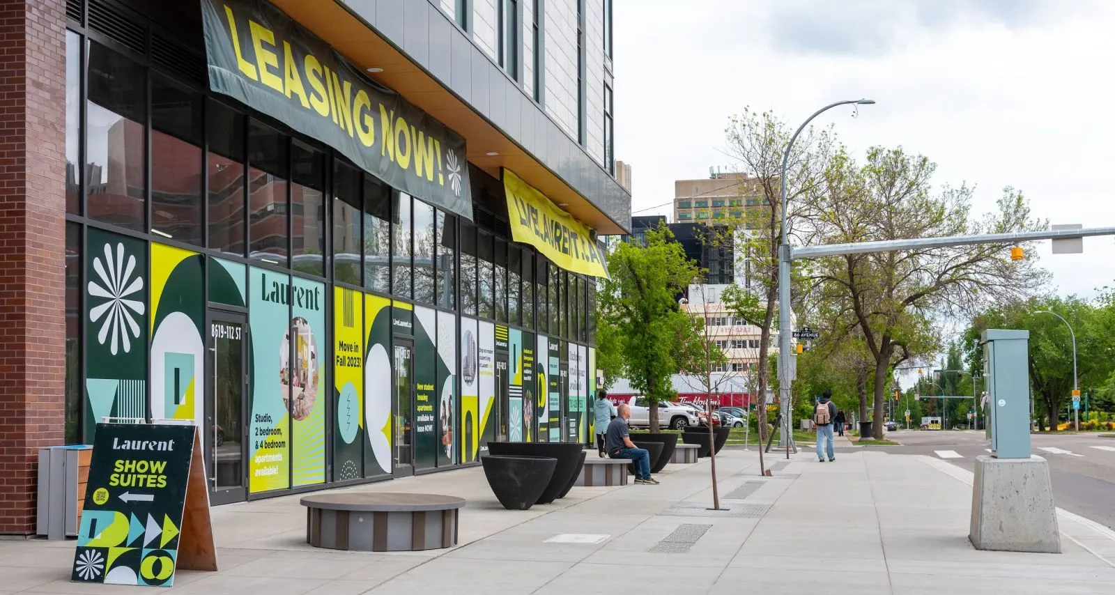Round benches provide seating outside a modern apartment building. The benches feature vertical slats and a concrete-like top.