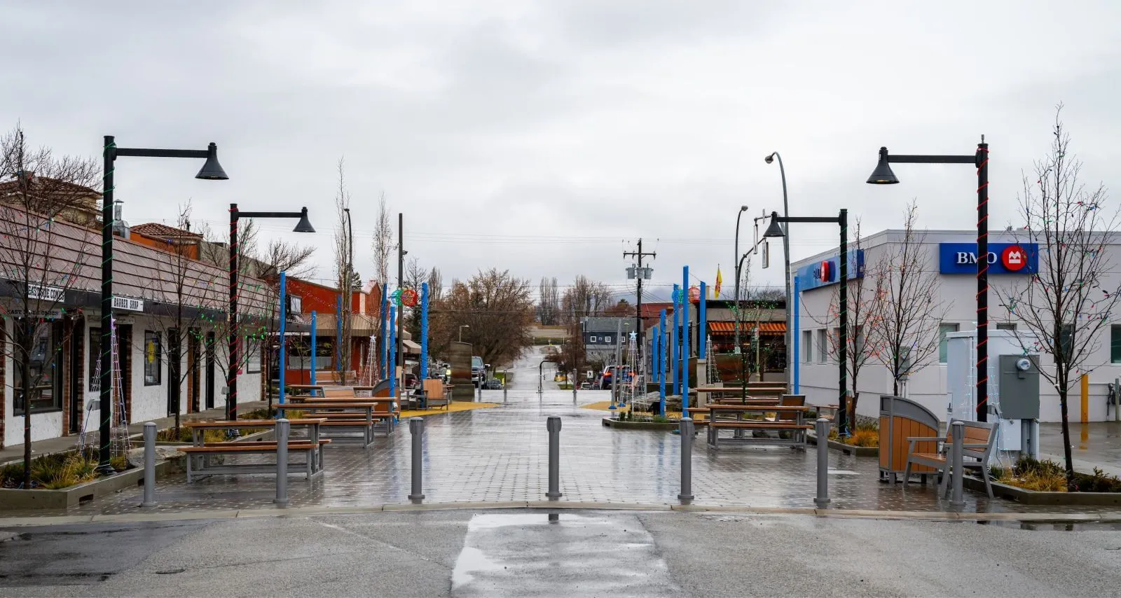 Streetscape featuring bollards and benches creates a pedestrian-friendly zone in Osoyoos, British Columbia. The outdoor furniture enhances the public space, providing seating and safety.