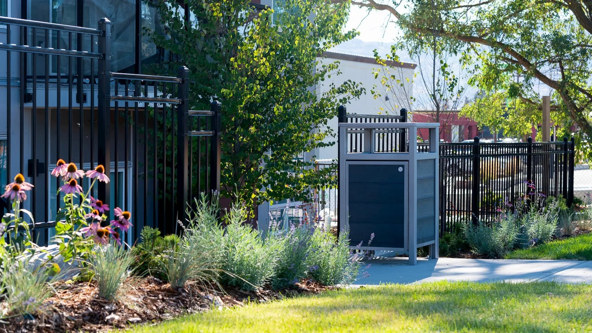 This Urban Form Easy Access Waste Receptacle is installed along a paved path in West Kelowna, BC. The litter bin features recycled plastic lumber and a powder-coated metal frame.