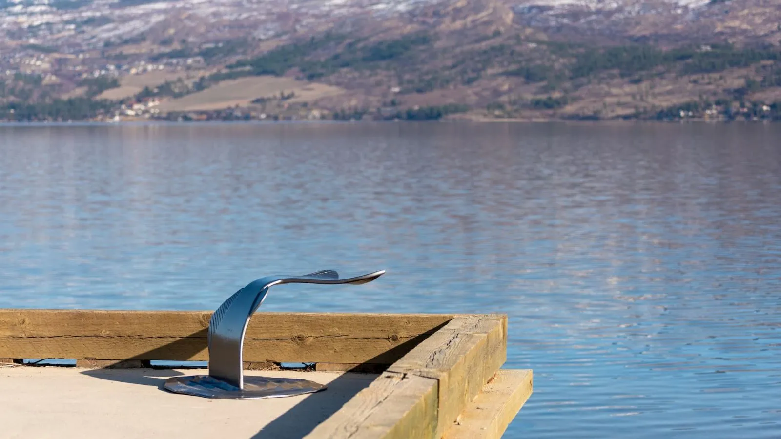 A Fishtail Seat provides a unique place to rest and enjoy the view from a wooden dock overlooking a lake and mountains.