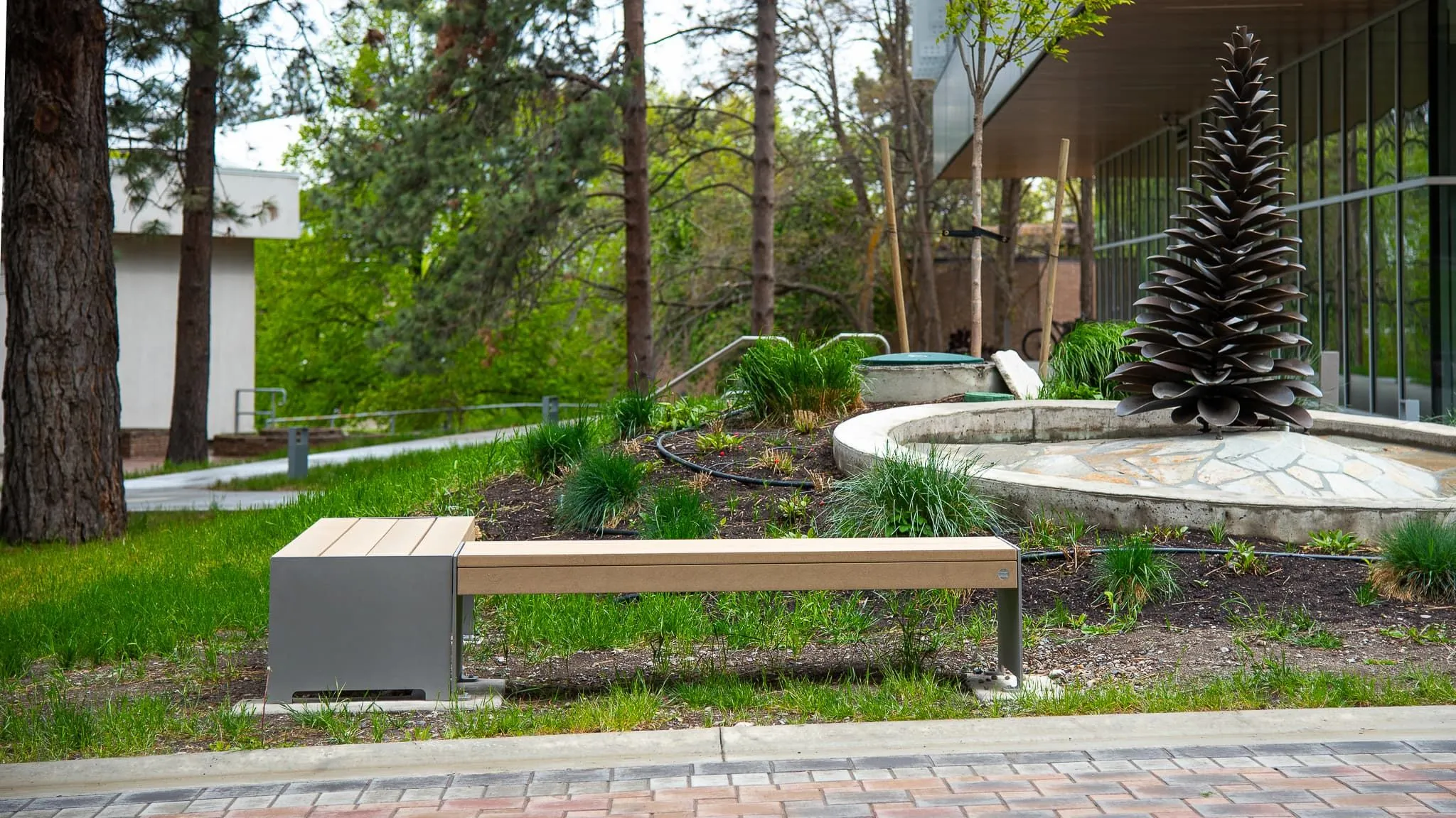 Hutch Backless Bench provides seating near a decorative fountain at Thompson Rivers University. The bench features recycled plastic lumber and a powder-coated metal frame.