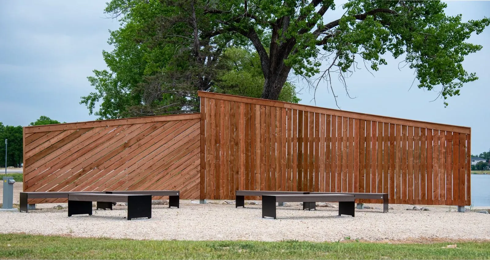 Hutch Backless Benches provide seating in an outdoor space with a wooden privacy screen. The benches feature recycled plastic lumber and powder-coated metal frames.