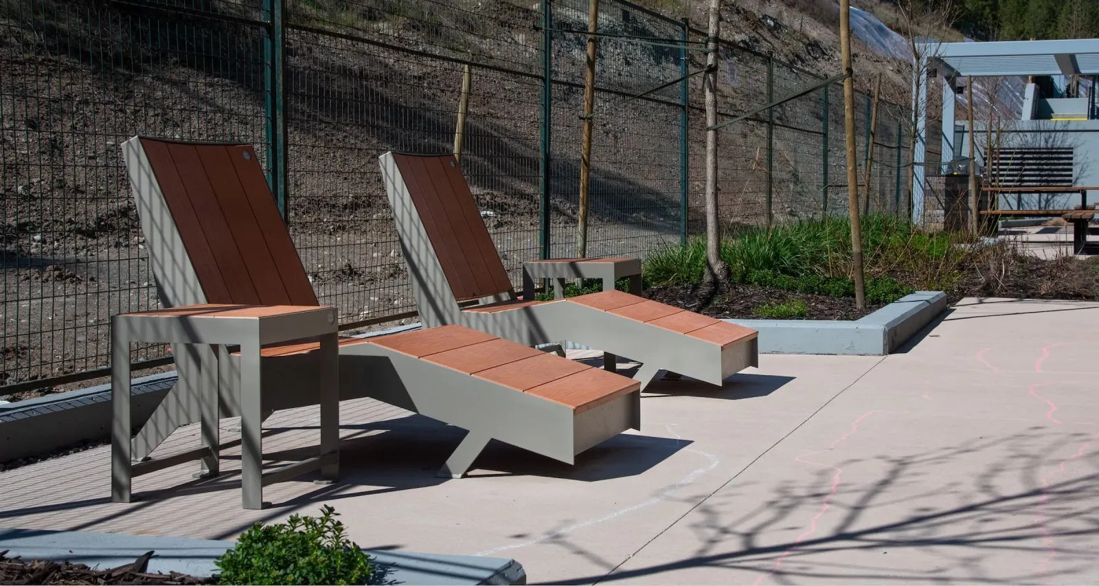 These chaise loungers offer a relaxing spot in an outdoor space. The seating features recycled plastic lumber and powder-coated metal frames.